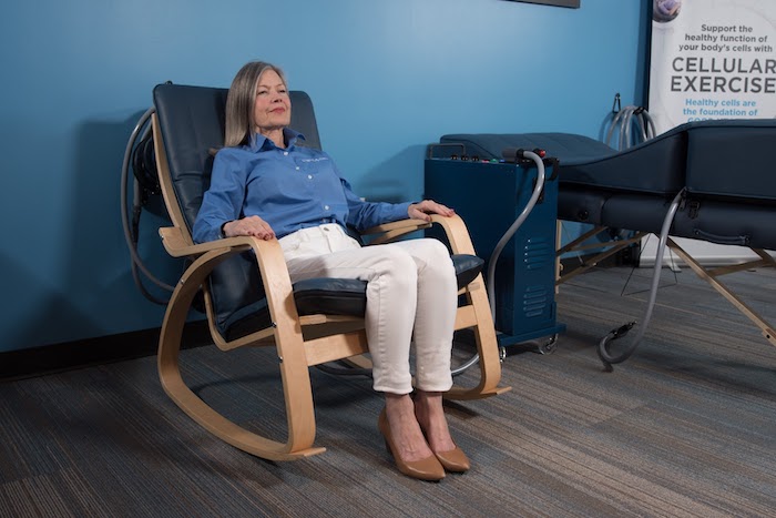 Woman relaxes in a chair on a PEMF chair paid