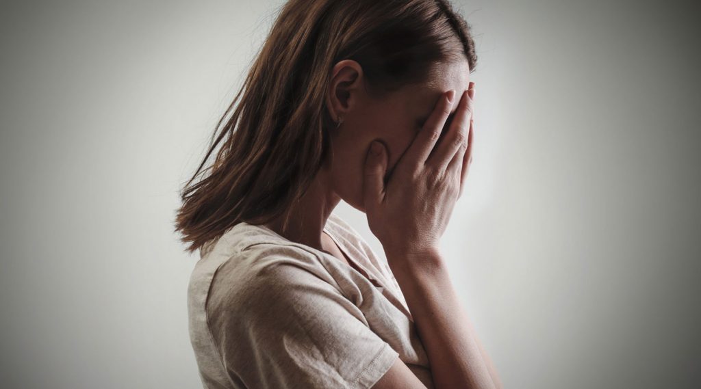 A woman hiding her face with her hands, possibly expressing embarrassment, sadness, or frustration.