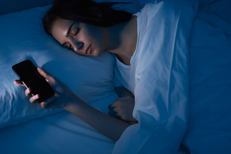 A woman sleeping in the bed with a phone in her hand