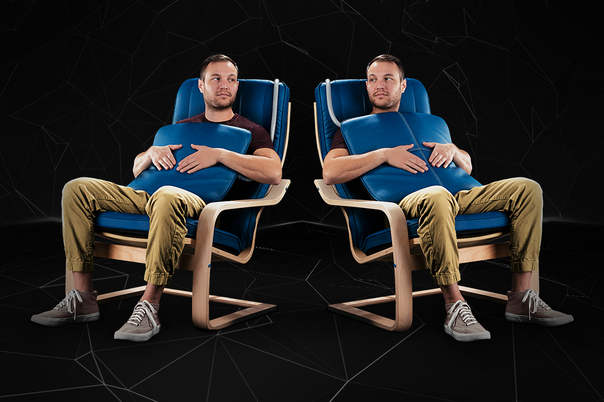 A mirror image of a man sitting in a PEMF Chair Pad With Chair while holding a PEMF pulse cube in his hands